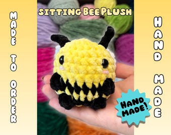 May include: A handmade, sitting bee plush toy. The plush is yellow with black stripes, antennae, and feet. The text "SITTING BEE PLUSH" is at the top, and "HAND MADE!" is on a blue star-shaped tag. The words "MADE TO ORDER" are on the left.