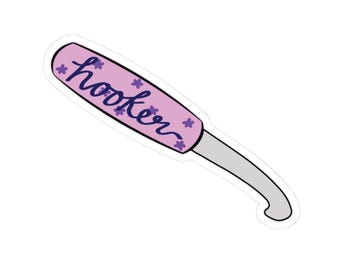 May include: A sticker featuring a crochet hook with a lavender handle and a silver hook. The handle has the word "hooker" in a dark blue script, with small purple flower accents.