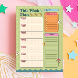 Puede incluir: Un bloc de notas planificador semanal con un fondo verde claro y un diseño ondulado. El bloc de notas incluye secciones para cada día de la semana, una sección "No olvidar" y una sección de notas. El texto "This Week's Plan" está en la parte superior.