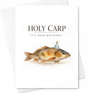 Może przedstawiać: Biała kartka z życzeniami z akwarelową ilustracją karpia w czapeczce urodzinowej. Tekst "HOLY CARP" i "IT'S YOUR BIRTHDAY!" są wydrukowane nad rybą. Karta jest w białej kopercie.