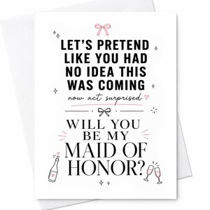 Op de afbeelding: Een witte wenskaart met zwarte tekst: LET'S PRETEND LIKE YOU HAD NO IDEA THIS WAS COMING now act surprised WILL YOU BE MY MAID OF HONOR? De kaart bevat kleine roze strikjes, hartjes, een champagnefles en twee glazen als decoratie.
