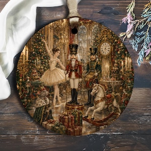 May include: A round ceramic ornament featuring a detailed illustration of a Nutcracker scene. The image depicts a ballerina in a gold dress, two toy soldiers, a mouse king, a rocking horse, and wrapped gifts in a festive room with a clock.