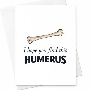 May include: A white greeting card with a humorous message. The card features a cartoon illustration of a bone and the text "I hope you find this HUMERUS" in black font. The card is inside a white envelope.