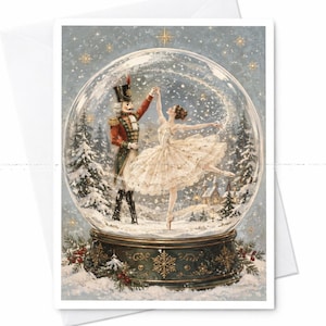 May include: A greeting card featuring a snow globe illustration with a nutcracker in a red uniform and a ballerina in a white tutu dancing inside. The base is dark green with gold snowflake accents, set against a snowy winter forest scene.