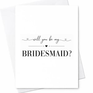 Op de afbeelding: Witte wenskaart met de tekst "will you be my BRIDESMAID?" in zwart schrift en een hartsymbool. De kaart zit in een witte envelop.