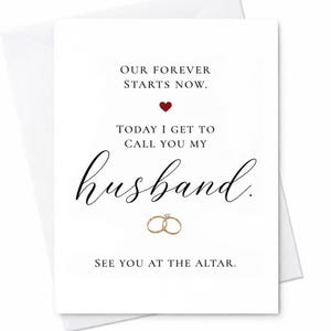 May include: A white greeting card featuring black text that reads: OUR FOREVER STARTS NOW. TODAY I GET TO CALL YOU MY husband. SEE YOU AT THE ALTAR. A small red heart is centered above the text, and two gold wedding rings are illustrated below.
