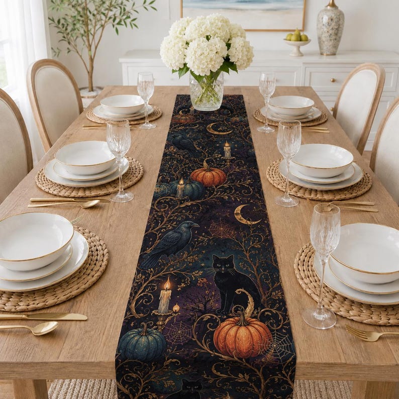 Peut inclure: Un chemin de table &agrave; th&egrave;me sombre orn&eacute; d'un motif r&eacute;p&eacute;titif de chats noirs, de corbeaux, de citrouilles orange, de toiles d'araign&eacute;e, de croissants de lune et de bougies allum&eacute;es sur un fond bleu marine, pos&eacute; sur une table en bois.