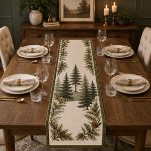May include: A rectangular table runner featuring a printed design of evergreen trees and pinecones on a cream background with a dark green border, centered on a wooden dining table set with white plates, napkins, and clear glassware.
