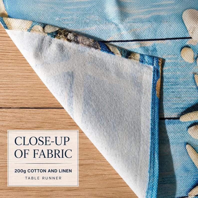 Peut inclure: Un chemin de table en tissu de coton et lin de 200g avec un imprim&eacute; c&ocirc;tier bleu et blanc et des motifs d'&eacute;toiles de mer. Le tissu est pli&eacute; pour r&eacute;v&eacute;ler le tissage textur&eacute; et l'envers. Le texte CLOSE-UP OF FABRIC 200g COTTON AND LINEN TABLE RUNNER est visible.