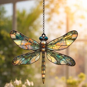 May include: A stained glass dragonfly suncatcher with iridescent wings in shades of green, yellow, and blue. The dragonfly has a bronze-colored metal frame and is suspended by a chain. Decorative beads accent the body and wings. A beautiful home decor item.