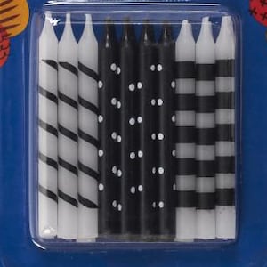 May include: A pack of birthday candles with the Bakery Crafts logo. The candles are black and white, with striped, dotted, and spiral designs. The package reads "BIRTHDAY CANDLES" and "20 PIECES 5.7 cm". The background is blue with colourful circles.