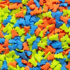 Könnte beinhalten: Nahaufnahme einer Vielzahl von bunten Dinosaurier-Streuseln. Die Streusel sind in Blautönen, Grün- und Orangetönen.