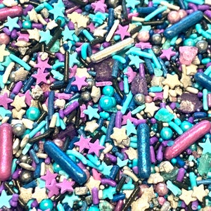 Könnte beinhalten: Eine Mischung aus blauen, violetten, silbernen und schwarzen Streuseln in Form von Sternen und Stäbchen.