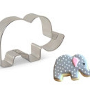 May include: A silver metal cookie cutter shaped like an elephant. The cutter is shown next to a decorated grey elephant cookie with white polka dots.