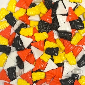 May include: A variety of colorful sprinkles in the shape of construction cones, dump trucks, and triangles. The sprinkles are perfect for decorating cakes, cupcakes, and other treats.