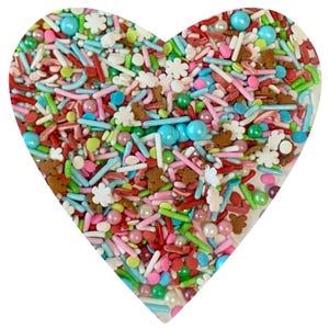 May include: A heart-shaped bowl filled with colorful sprinkles, including red and white candy canes, green and white snowflake sprinkles, and small, round, pastel-colored sprinkles.