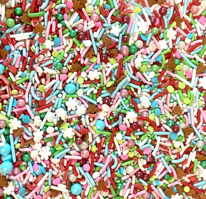 May include: A colorful mix of sprinkles for baking and decorating. The sprinkles include red, green, white, blue, and brown sprinkles in various shapes and sizes.