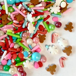 May include: A variety of colorful sprinkles, including red and white candy canes, gingerbread men, white snowflakes, and pastel-colored balls and rods.