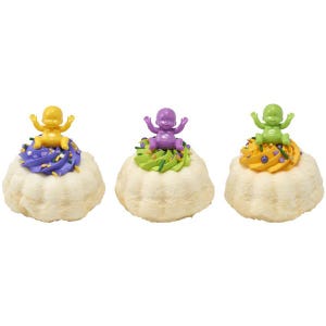 May include: Three small, white, cloud-shaped cakes topped with colorful frosting and plastic baby figurines. The frosting colors are purple, green, and orange, with sprinkles. The baby figurines are yellow, purple, and green.