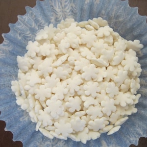 Puede incluir: Un molde para magdalenas de papel azul lleno de espolvorear de copos de nieve blancos.