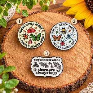 May include: Three enamel pins featuring insect illustrations and the text 'YOU'RE NEVER ALONE THERE'S ALWAYS BUGS' or 'you're never alone there are always bugs'. Two pins are circular with colourful bugs, and one is a rectangular shape with black line art.