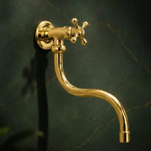 Peut inclure: Un robinet doré avec un bec courbé et des poignées en forme de croix. Le robinet est monté sur un mur vert foncé. Le design est vintage et élégant, adapté à une cuisine ou une salle de bain. Mesures en centimètres.