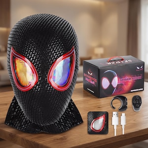 May include: A black Spider-Man visor with red-rimmed eye lenses. The visor is made of a textured material and sits on a wooden surface. A box and accessories are also present, including a remote and charging cables.