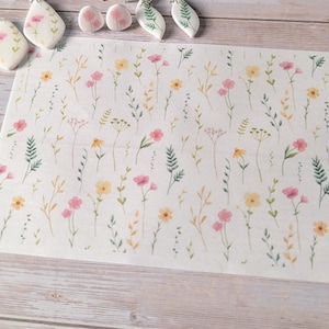 Peut inclure: Un ensemble de boucles d'oreilles florales faites à la main et une impression florale assortie. Les boucles d'oreilles sont blanches avec des motifs floraux roses et verts. L'impression présente un motif aquarelle de fleurs roses et jaunes et de feuilles vertes.