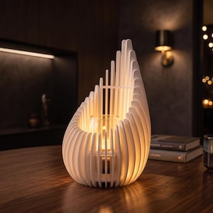 May include: A white, flame-shaped candle holder constructed from vertical slats that curve upward. The structure features a central clear glass insert designed to hold a candle, which emits a warm, soft glow from within the slatted frame.