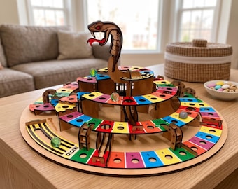 May include: A multi-tiered circular wooden board game featuring a central cobra figure with a red tongue. The game board has colorful numbered spaces in red, yellow, blue, and green, with the word INICIO printed at the start and glass marbles.