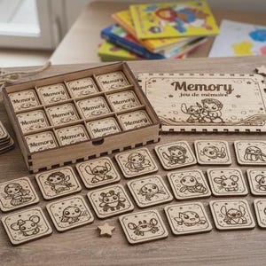May include: A wooden memory game set featuring a rectangular storage box, a matching lid with the text "Memory Jeu de mémoire" and engraved cartoon characters, and numerous square tiles with various engraved character illustrations.