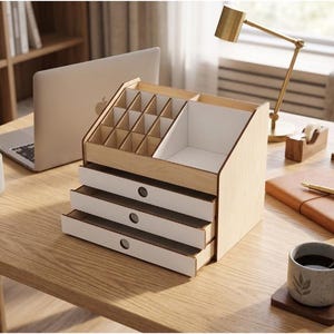 May include: A light wood desk organizer featuring three white-fronted drawers, a grid of small square compartments, and a larger open storage section. The unit has a slanted top design with a natural wood finish and white interior accents.