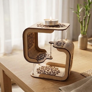 May include: A light-colored wooden candle holder featuring a tensegrity structure with three floating platforms connected by thin white strings. Each platform is decorated with a laser-cut mandala pattern. A single white tea light candle sits on top.