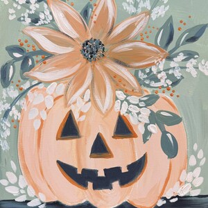 May include: A painting of a light orange jack-o'-lantern with dark triangular eyes and a jagged mouth. A large, pale peach flower sits atop the pumpkin, surrounded by dark green leaves, white floral sprigs, and small orange dots on a sage background.