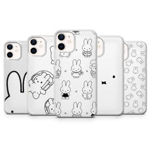 Op de afbeelding: Een verzameling witte telefoonhoesjes met zwart-witte illustraties van een konijn. De ontwerpen omvatten een konijnomtrek, een konijn met een mand en verschillende konijnenpersonages in verschillende outfits. De hoesjes zijn in een rij gerangschikt.