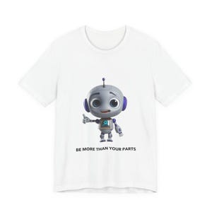 May include: A white short-sleeved t-shirt featuring a graphic of a small, round, grey robot with large blue eyes and purple ear pieces. The robot is giving a thumbs up. Below the robot, the text reads, BE MORE THAN YOUR PARTS in black.