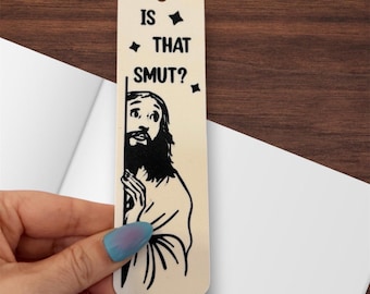 May include: A rectangular light-colored bookmark with a hole at the top. It features a black graphic illustration of a bearded figure peeking from behind a vertical line, accompanied by the black text "IS THAT SMUT?" and small star icons.