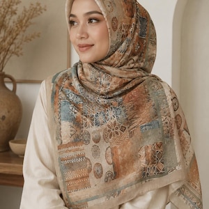 May include: A square headscarf featuring a patchwork design with muted earth tones including brown, tan, and faded blue. The pattern consists of various geometric shapes, floral motifs, and circular medallions printed across the fabric surface.