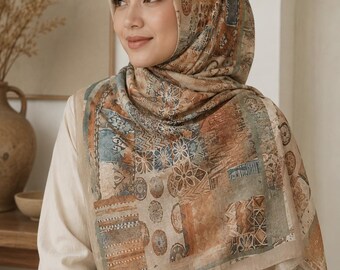 Op de afbeelding: Een vierkante hoofddoek met een patchworkontwerp in gedempte aardetinten, waaronder bruin, beige en vervaagd blauw. Het patroon bestaat uit diverse geometrische vormen, bloemmotieven en cirkelvormige medaillons op de stof.