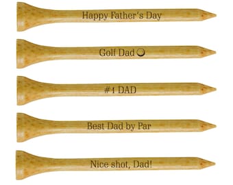Puede incluir: Conjunto de cinco tees de golf de madera con mensajes grabados: "Feliz Día del Padre", "Papá golfista", "#1 PAPÁ", "Mejor papá por", y "Buen tiro, papá!"