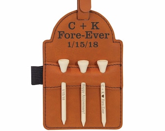 May include: Brown leather golf ball holder with three golf tees. The holder has a strap for attaching to a golf bag. The holder is personalized with the text "C+K Fore-Ever 1/15/18".