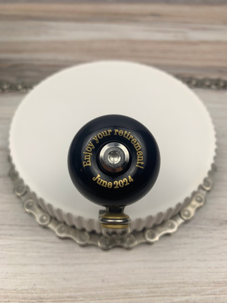 May include: Black bicycle bell with gold lettering that reads "Enjoy your retirement! June 2024".