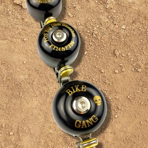 May include: Three black bike bells with gold lettering. The top bell says "Pos Big Deal Smasher FY24 & FY25". The middle bell says "Bike Gang" with a skull graphic.