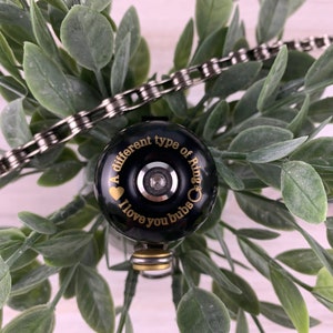 May include: A black bicycle bell with a gold inscription that reads "A different type of ring. I love you bubs."