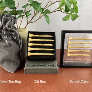 May include: A set of six personalized golf tees in a black gift box with a gray velvet bag. The tees are engraved with the text "Happy Father's Day", "Golf Dad", "#1 Dad", "Best Dad by Far", "Nice Shot, Dad!" and "Happy Father's Day".