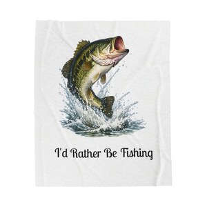 Peut inclure: Couverture blanche avec une illustration détaillée d'un achigan à grande bouche sautant hors de l'eau. Le poisson est vert, noir et beige, avec la bouche ouverte. Le texte "I'd Rather Be Fishing" est imprimé en dessous en noir.