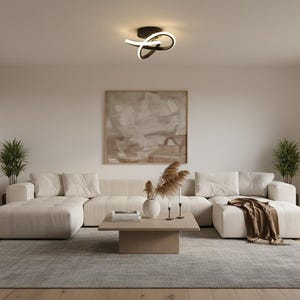 May include: A modern living room with a large, cream-colored sectional sofa, a square wooden coffee table, and a gray rug. The room features a neutral color palette, a large abstract painting, and two potted plants. A decorative light fixture hangs from the ceiling.