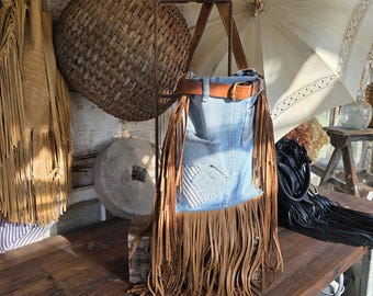 Bolso de tela vaquera reciclada con correa de cuero repujado vintage y flecos de estilo bohemio occidental.