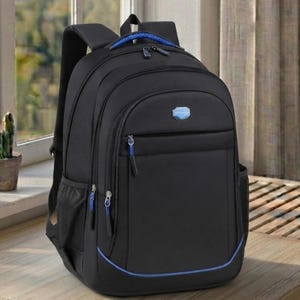 May include: A black backpack featuring multiple zippered compartments, a top handle with blue woven detailing, side mesh pockets, and a small blue rectangular logo patch on the front. The design includes blue zipper pulls and a thin blue accent line.