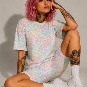 May include: A matching pastel leopard print t-shirt and biker shorts set. The top is short-sleeved, and the shorts are mid-thigh length. The outfit is paired with white sneakers and socks. The overall aesthetic is casual and comfortable.